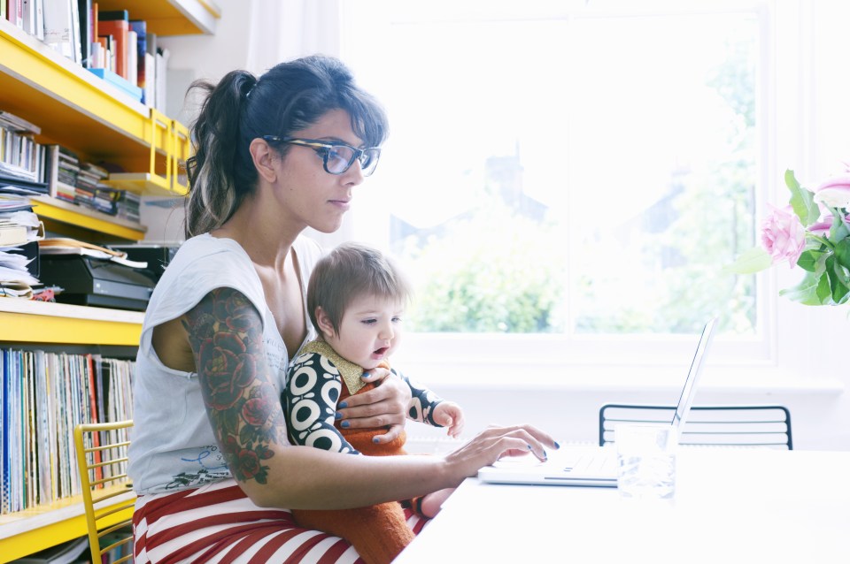 mother with baby in lap working on laptop at home