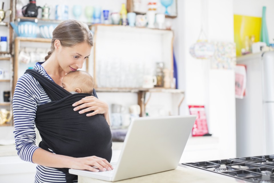 Mother with baby boy using laptop in kitchen