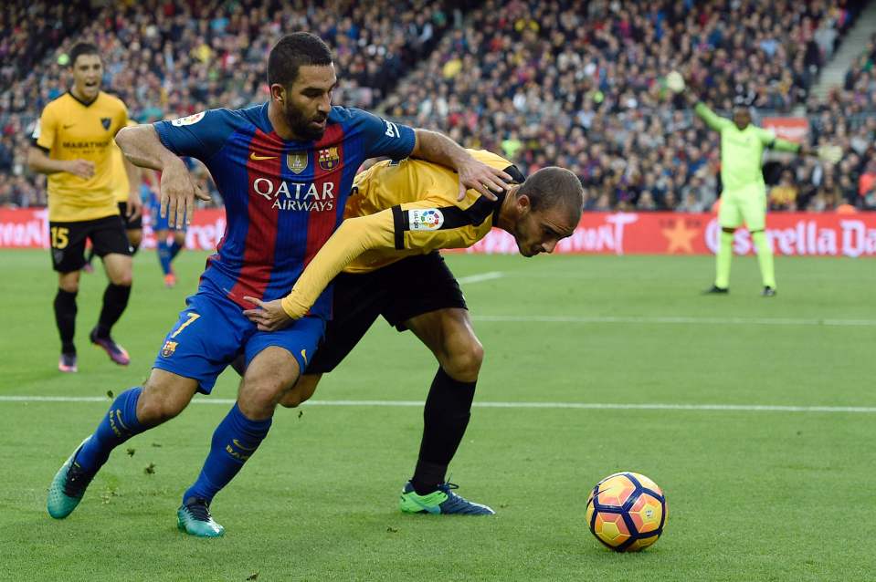 Barcelona's Turkish forward Arda Turan (L) vies with Malaga's Venezuelan defender Mikel Villanueva (R) during the Spanish league football match between FC Barcelona and Malaga CF at the Camp Nou stadium in Barcelona, on November 19, 2016. / AFP PHOTO / LLUIS GENELLUIS GENE/AFP/Getty Images