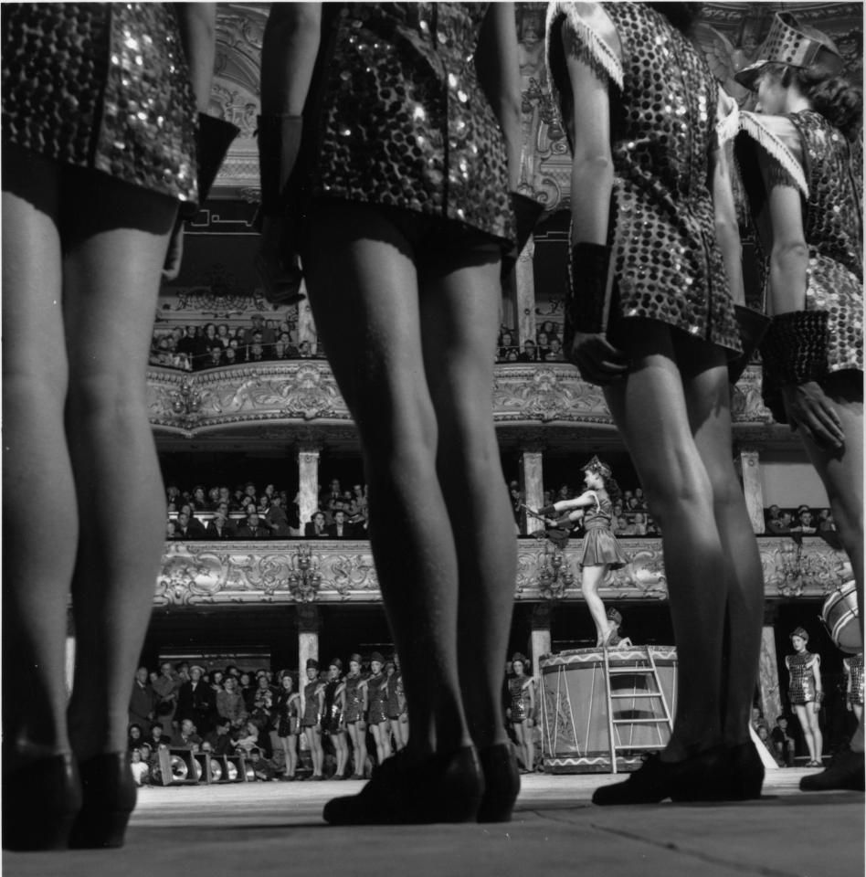  A cameraman sneaks a shot of the audience through the dancer's legs as they prepare to take a bow