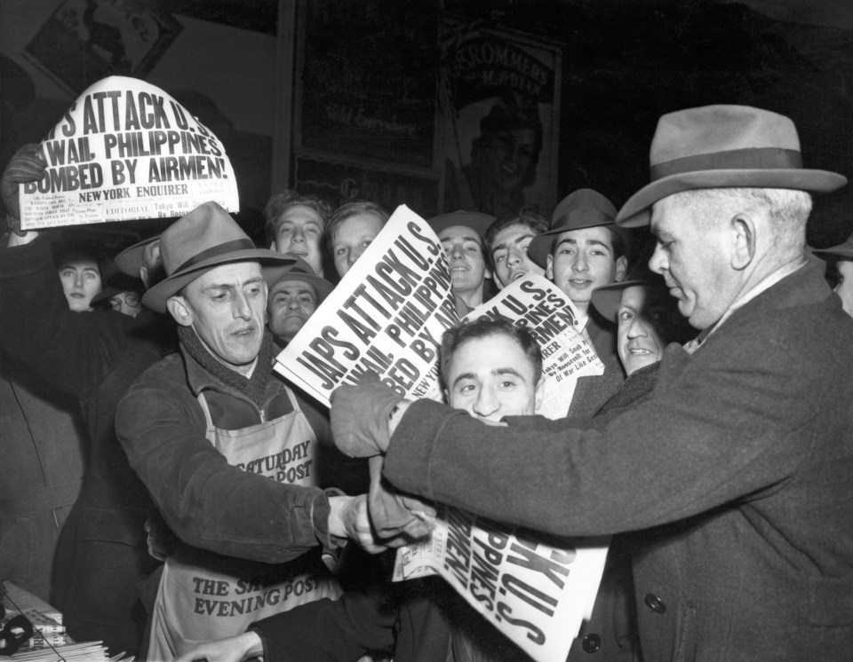 Shocked and angry crowds in Times Square grab New York Enquirer newspapers bearing the headlines of Japan's attack on the US