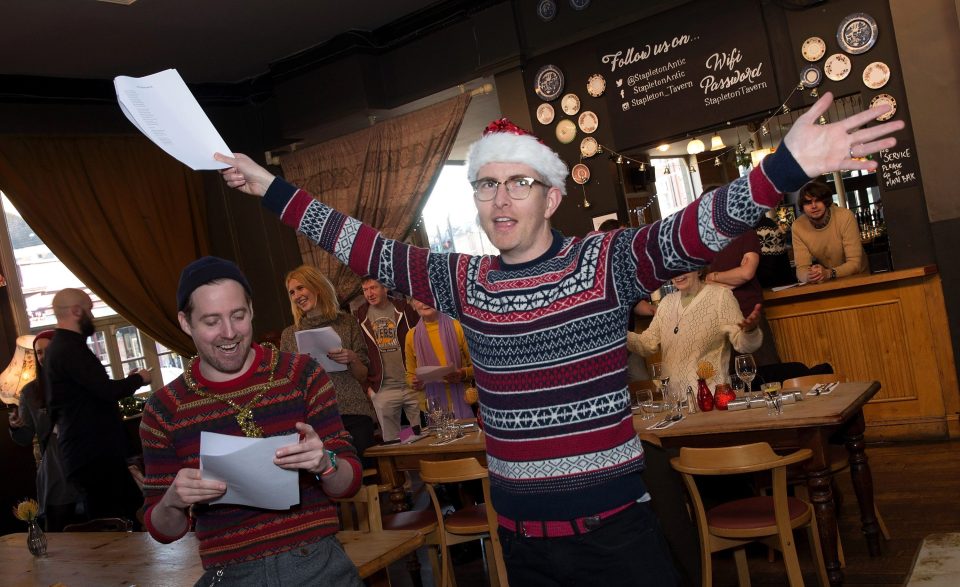 a man in a santa hat holds up papers in front of a sign that says follow us on