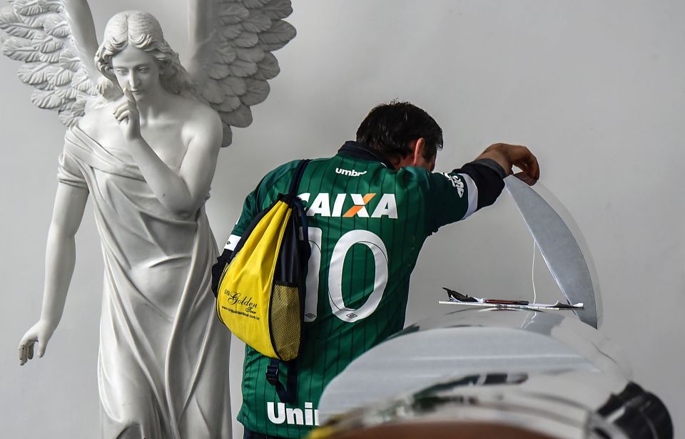 A relative of one of the deceased players inspects the coffin