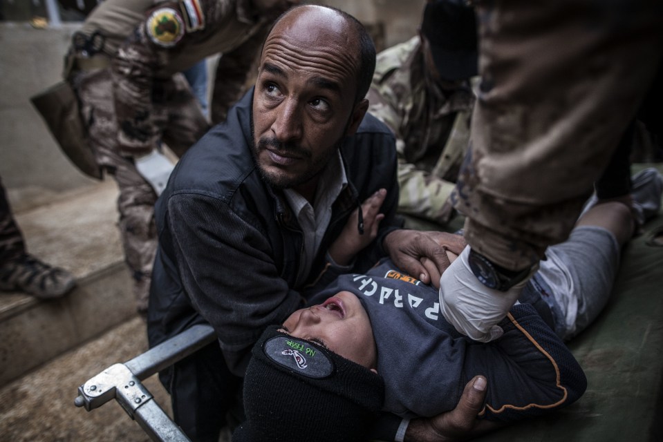  A man rescues an injured child from ISIS ... The battle for Mosul is causing increasing numbers of civilian casualties