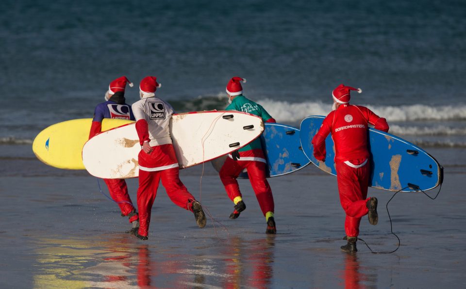 Surfers dressed as Santa run into the sea as they compete in a heat in Newquay