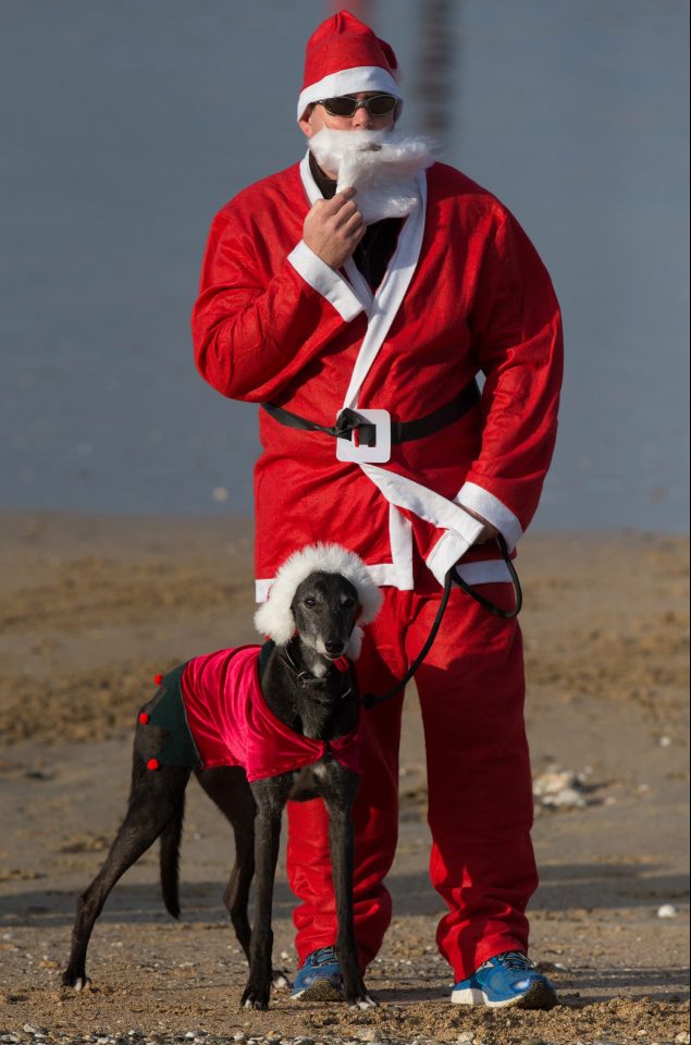 A man dressed as Santa stands with his dog as waits to take part in the beach fun run 