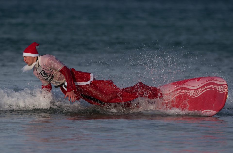 A surfing Santa takes a drop into the brutally cold waters off Newquay 