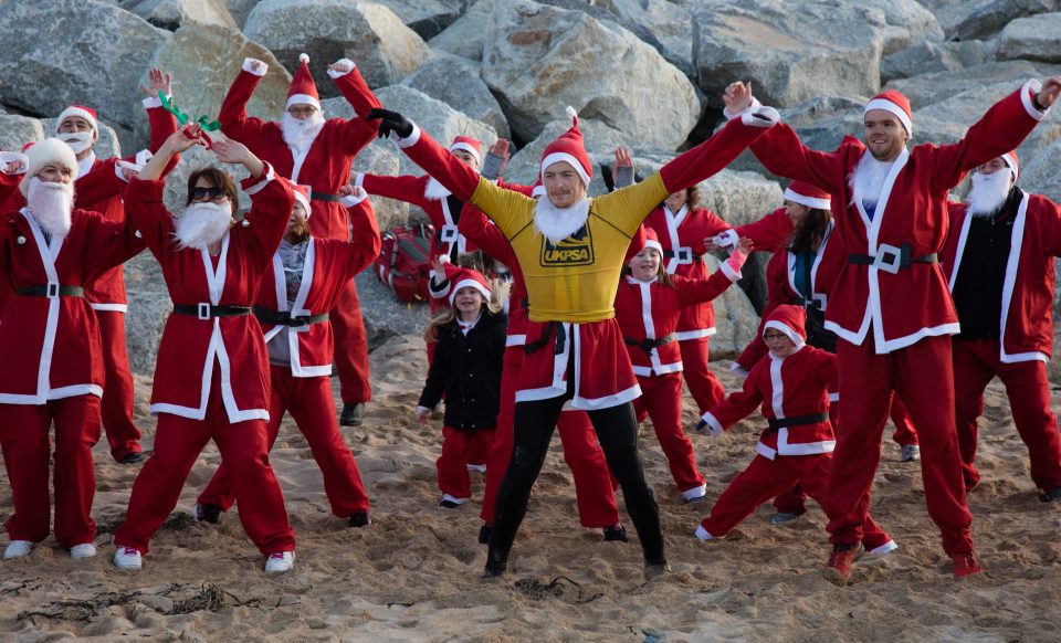 People dressed as Santa warm up prior to taking part in the beach fun run 