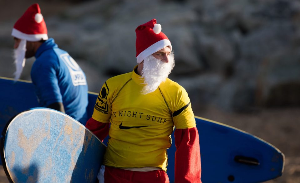 A surfer dressed as Santa prepares to brave the icy waves off Fistral Beach 