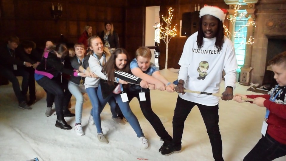 A volunteer helps as children at Scotty's contest a tug-of-war