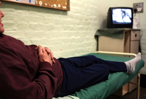 An elderly prisoner watches TV in his cell at Wandsworth prison.