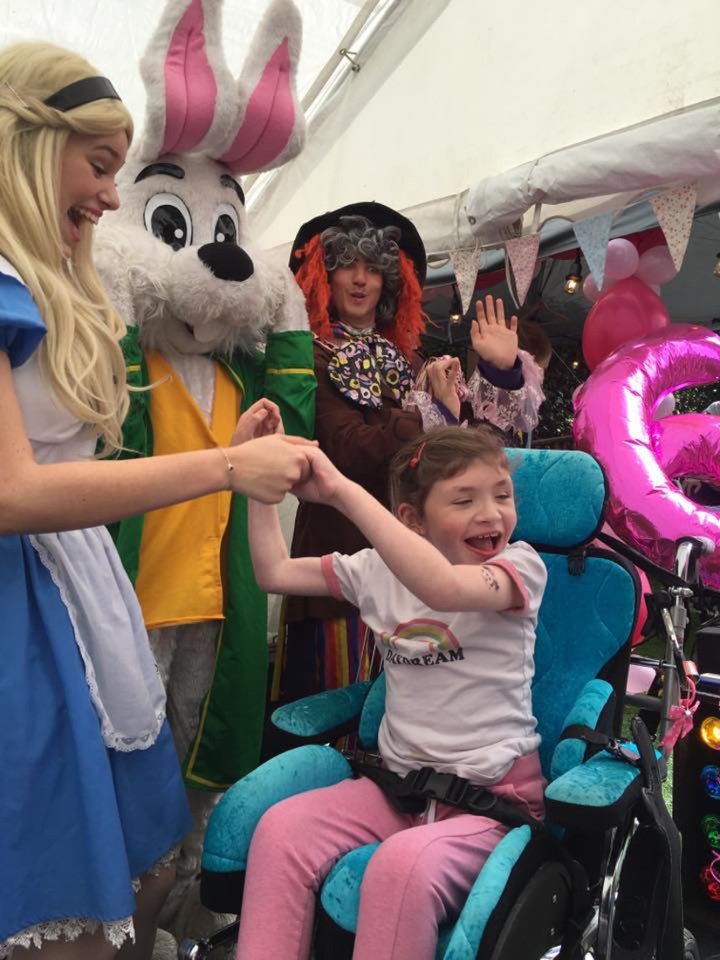 Jessica is all smiles at a friends birthday party as she plays with a lady dressed as Alice in Wonderland 