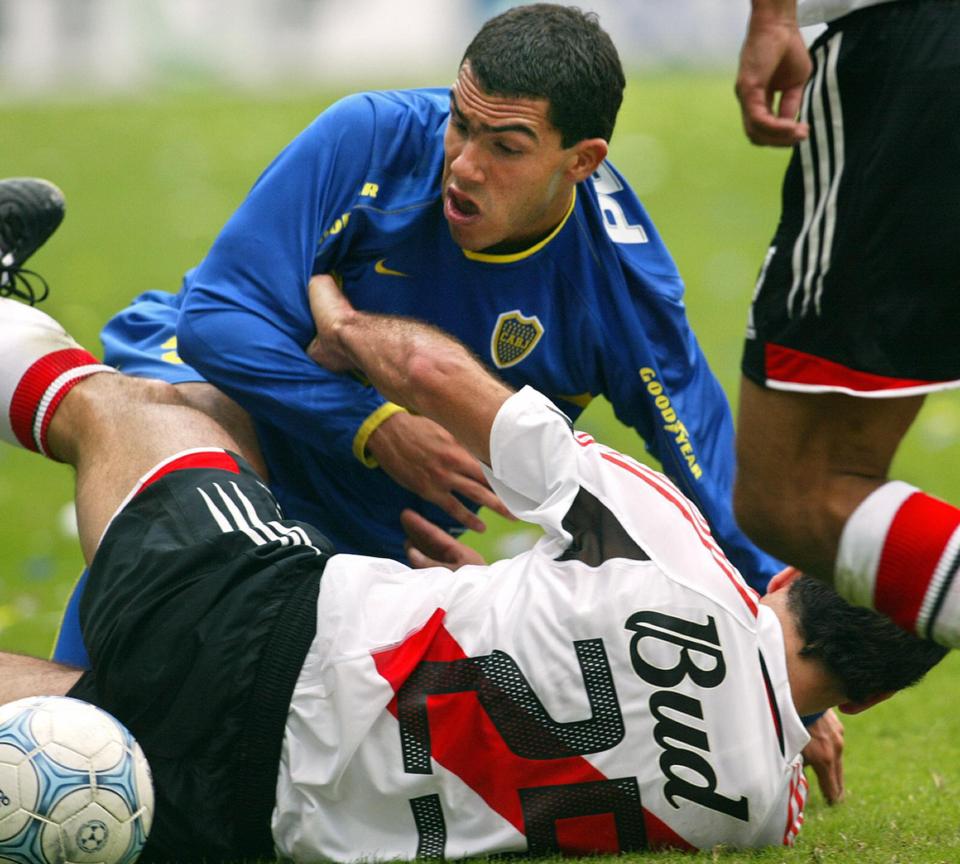 BUENOS AIRES, ARGENTINA: Carlos Tevez (top) of Boca Juniors fights for the ball with Eduardo Tuzzio of River Plate during the 14th round match of the Argentinean Closing Tournament in La Bombonera stadium in Buenos Aires, Argentina, 16 May 2004. River Plate won 1-0 and leads the champiomship. AFP PHOTO/Daniel GARCIA (Photo credit should read DANIEL GARCIA/AFP/Getty Images)