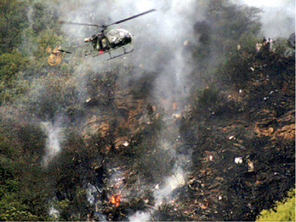  A helicopter flies over the crash site, which was said to smell of burning flesh