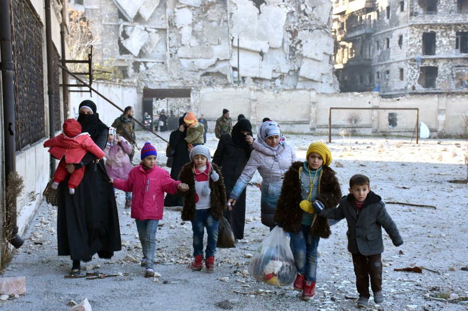  Civilians, who evacuated the eastern districts of Aleppo, carry their belongings as they arrive in a government held area