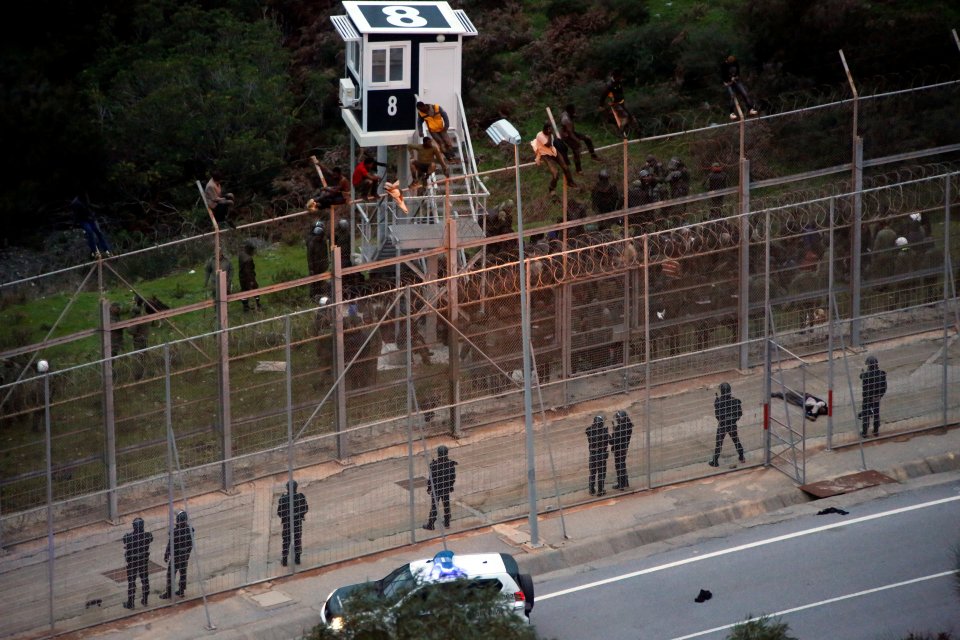  African migrants sit on top of a border fence during the successful attempt to cross into Spanish territories