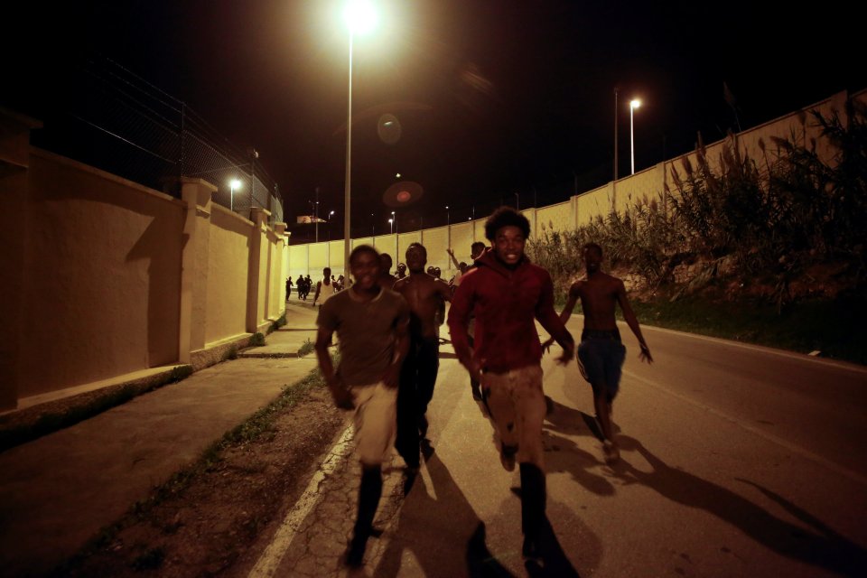  African migrants run on a road after crossing the border fence between Morocco and Spain's north African enclave of Ceuta