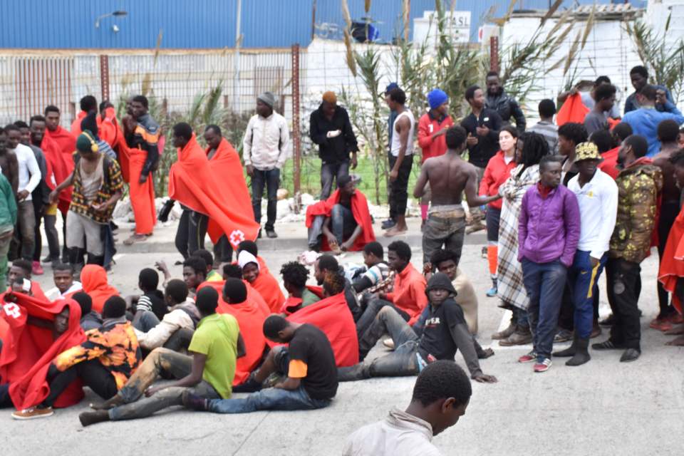  Migrants sit on the ground in El Tarajal after busting through the border