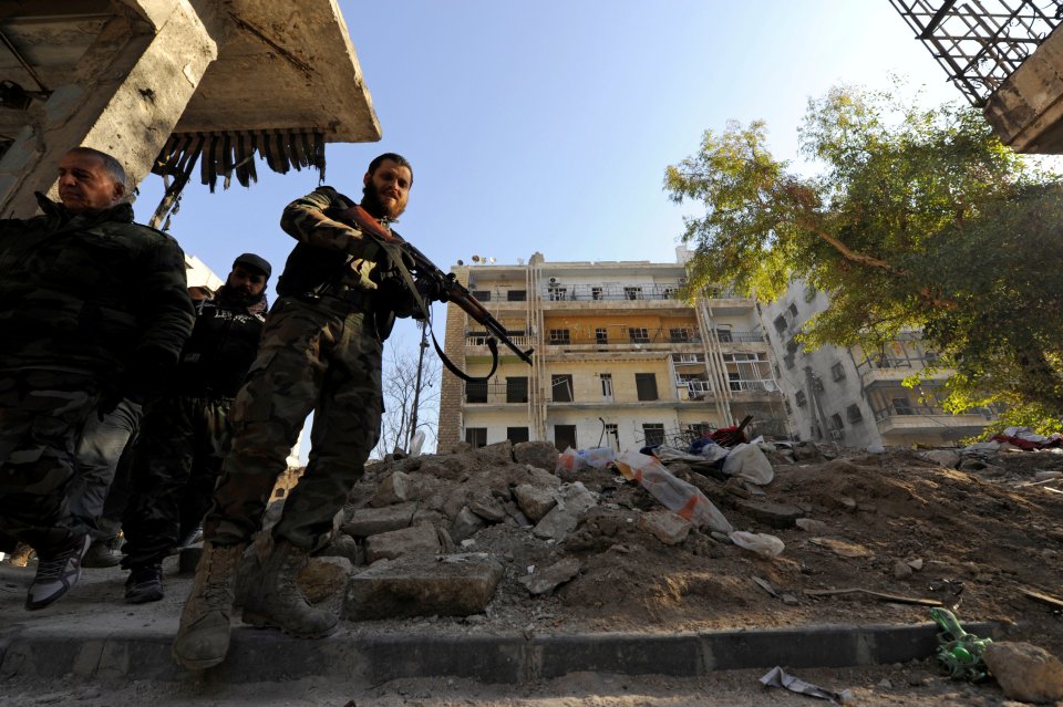  Forces loyal to Syria's President carry their weapons as they walk in a government captured area of Aleppo