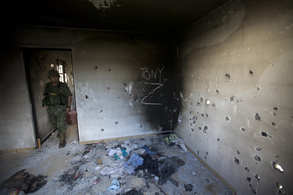  A soldier enters a bullet-riddled home, tagged with the initials CDG for the Gulf Cartel, and Z for Zetas, in Ciudad Victoria