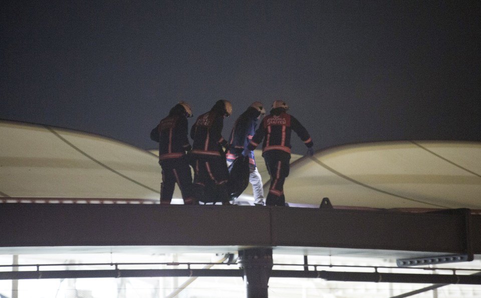 Firefighters carry a body off the roof 