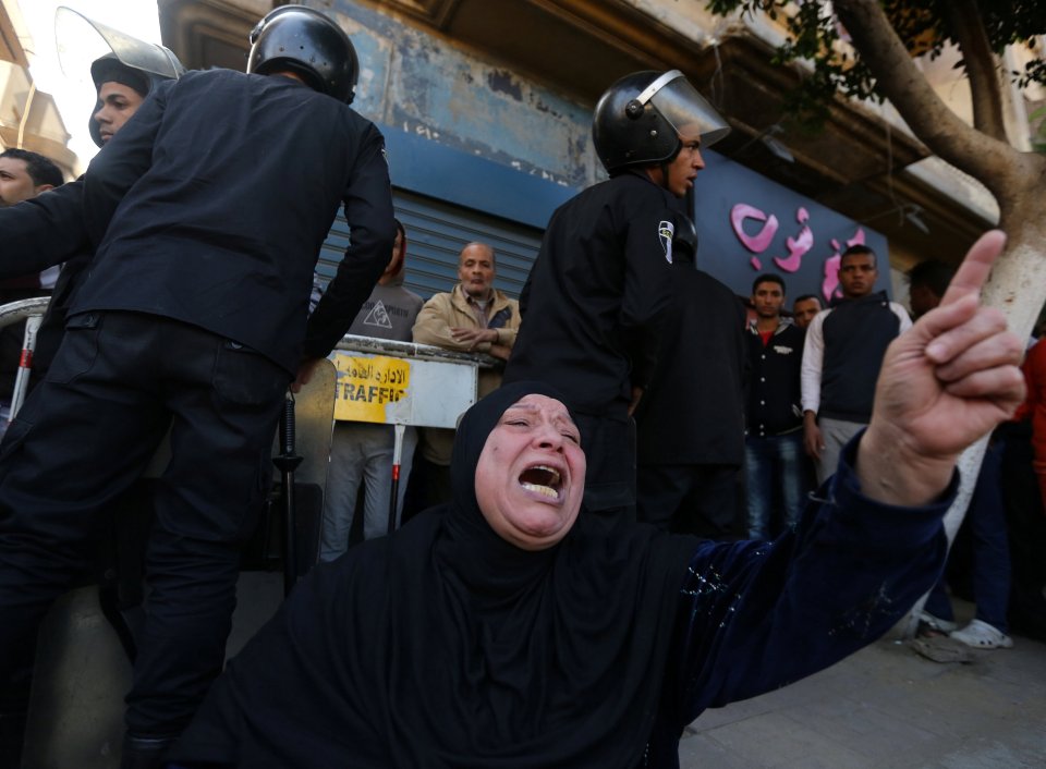 A Muslim woman cries while sitting in front of police officers at the scene