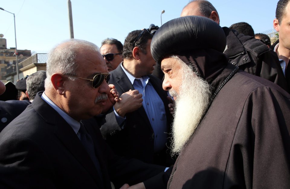 Egyptian Prime Minister Sherif Ismail speaks with a Coptic priest outside the church