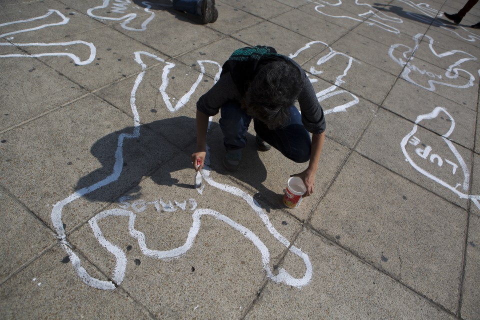  A woman paints the name of a victim of the Mexican drug war onto a body outline in Mexico City