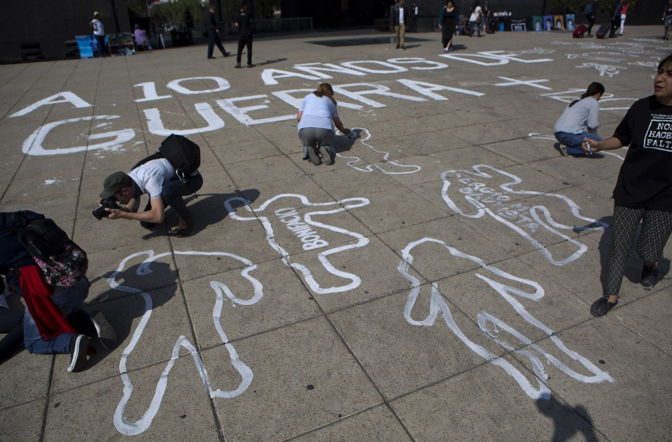  People paint outlines of bodies as part of a memorial for those killed, on the 10th anniversary of the drug war's start