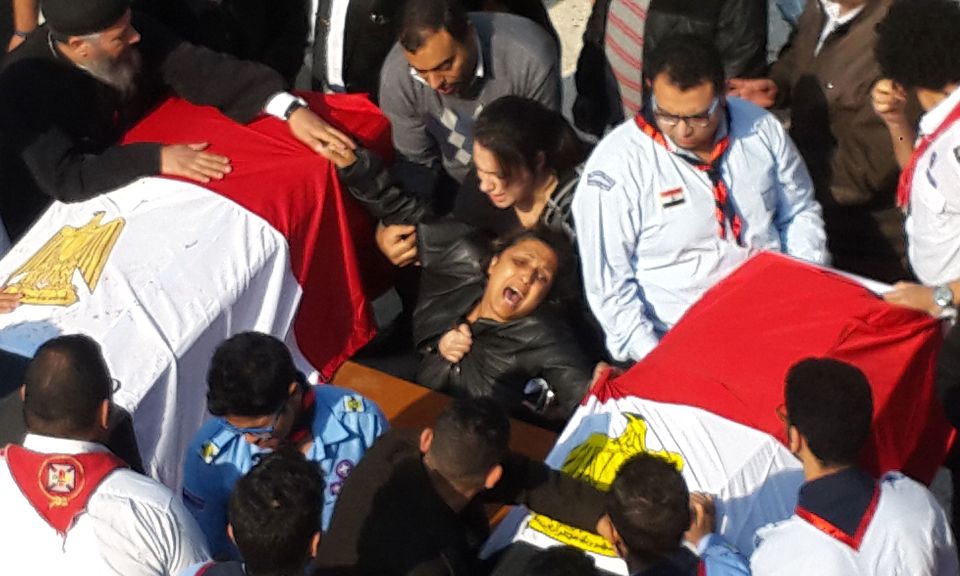  An woman breaks down next to the coffins of her two daughters in Cairo today