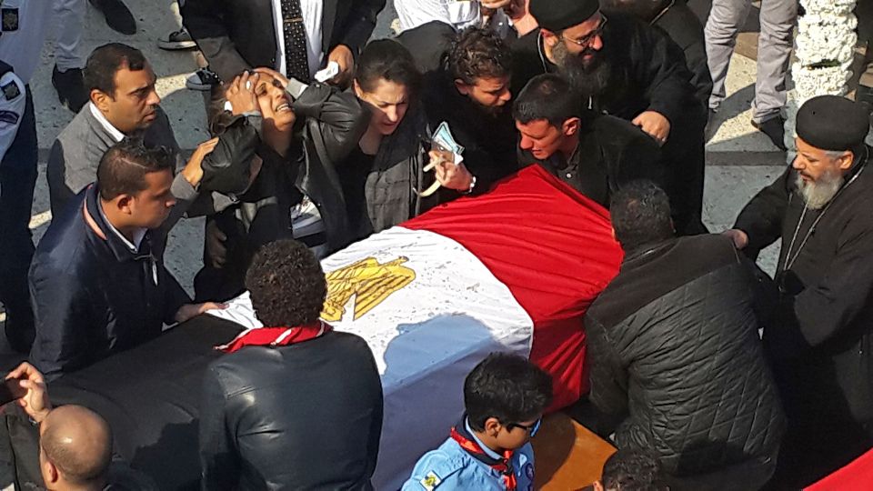  A woman cries next to the coffins of her two daughters before they are taken away