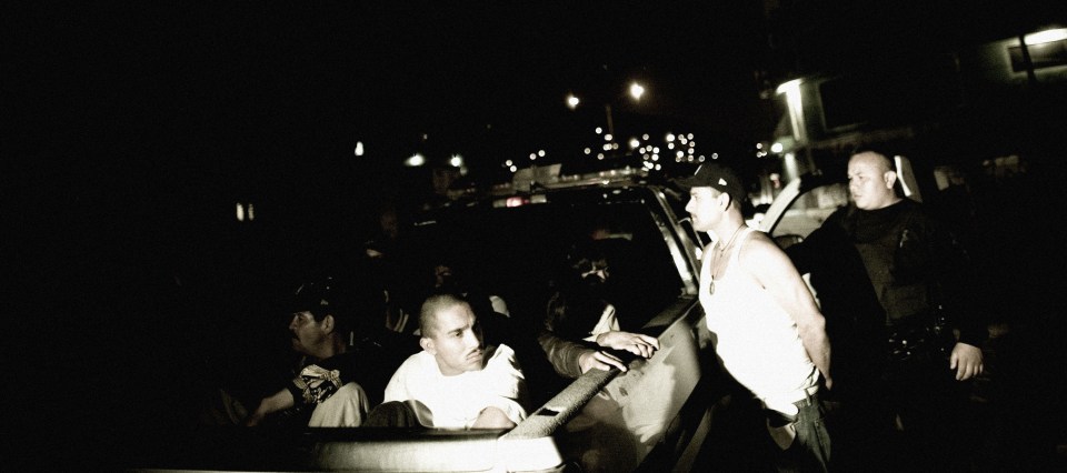  Suspects sit in the back of a police pickup truck after being arrested on a night raid in Tijuana