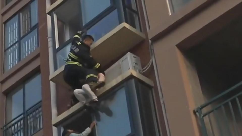  The daring fireman abseils down and grabs the woman to try to pull her to safety