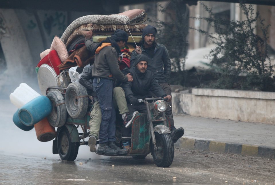  Men ride a tricycle as they flee deeper into the remaining rebel-held areas of Aleppo