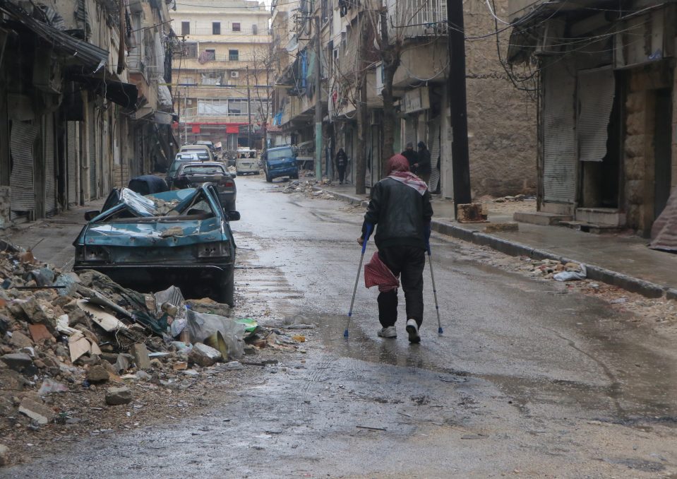  A man stuck in the al-Mashhad neighborhood, walks with crutches to reach an evacuation site