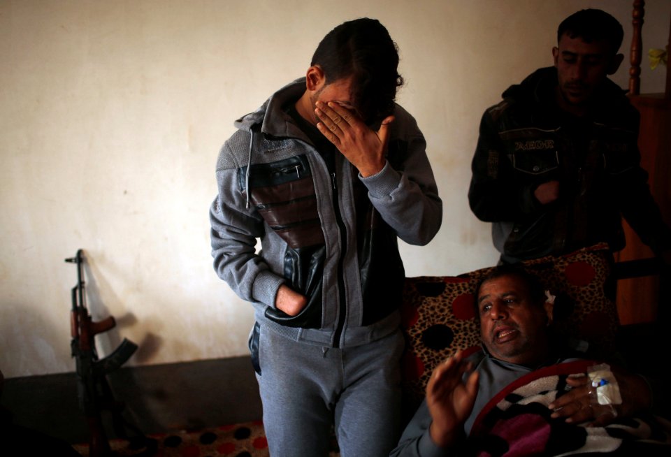  Azad cries as he stands beside his wounded father in a house at Nimrud village, south of Mosul