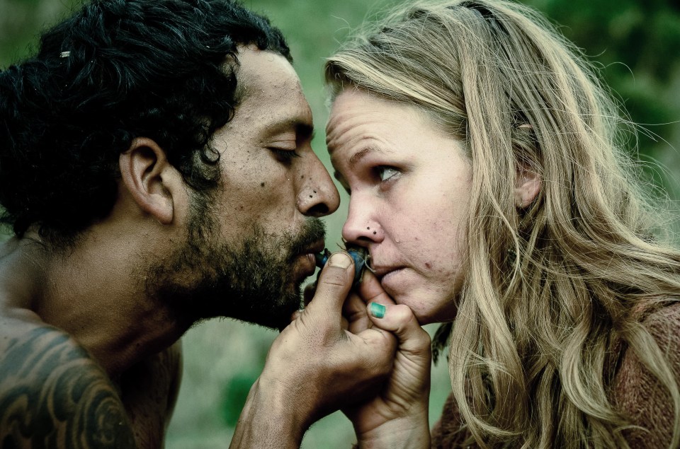 a man with a tattoo on his arm kisses a woman on the nose