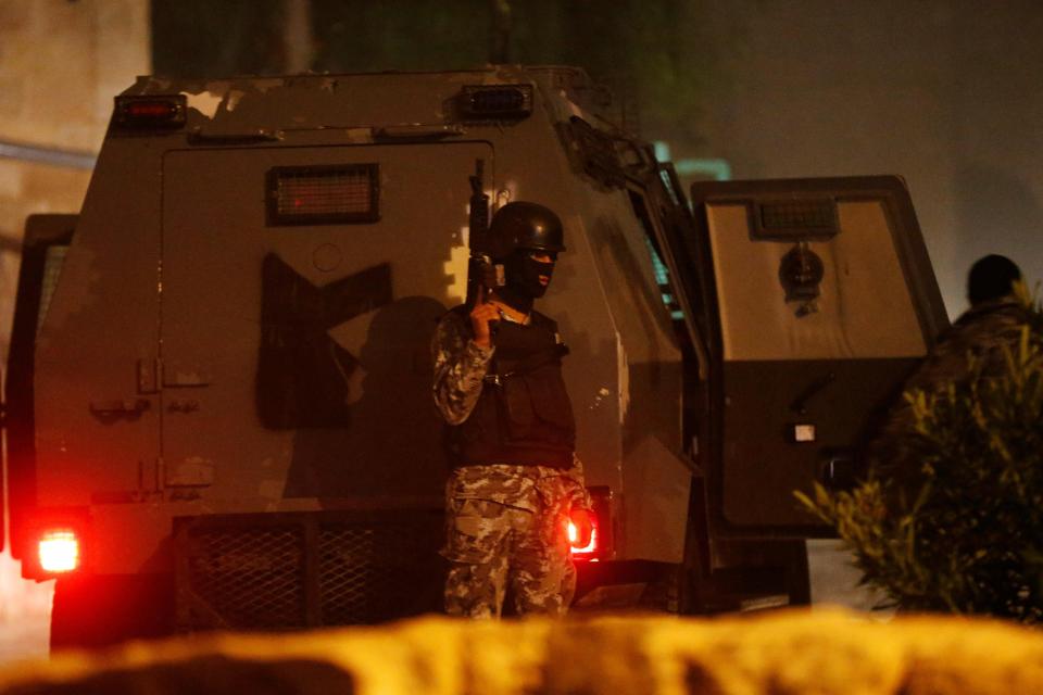  A heavily armed Jordanian cop stands guard at the scene of the raid