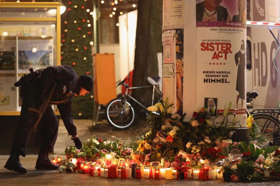 A police officer places tributes at a makeshift memorial