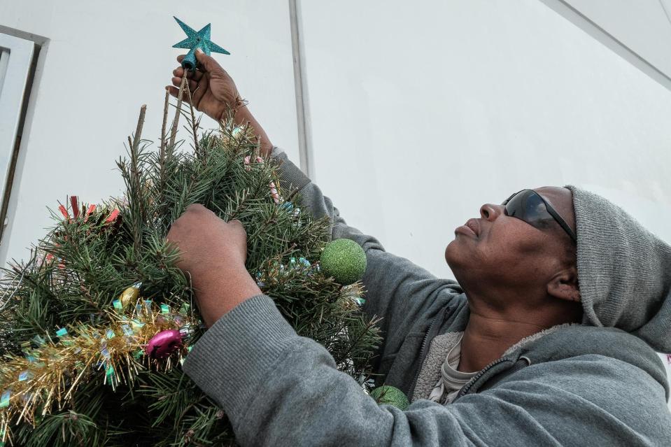 She adjusts star at the top on one of the few visible Christmas trees on Skid Row