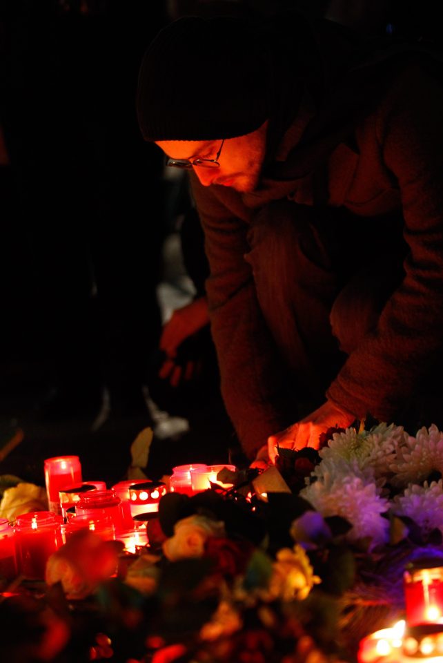 A man lights a candle as he pays his respects to those who lost their lives