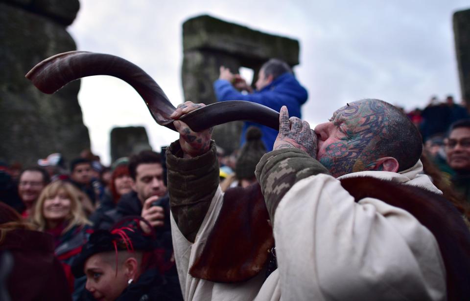  A heavily-tattooed reveller blows a horn amid jubilant scenes at Stonehenge