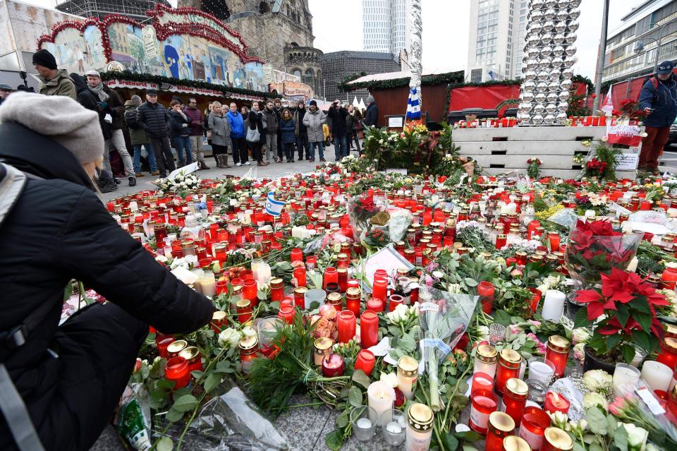 a mass of candles and floral tributes placed at the recently re-opened Christmas Market