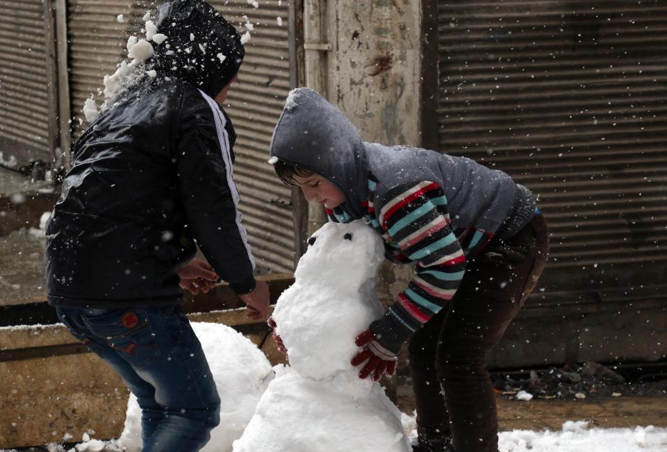  Syrian children make a snow man in the town of Maaret al-Numan