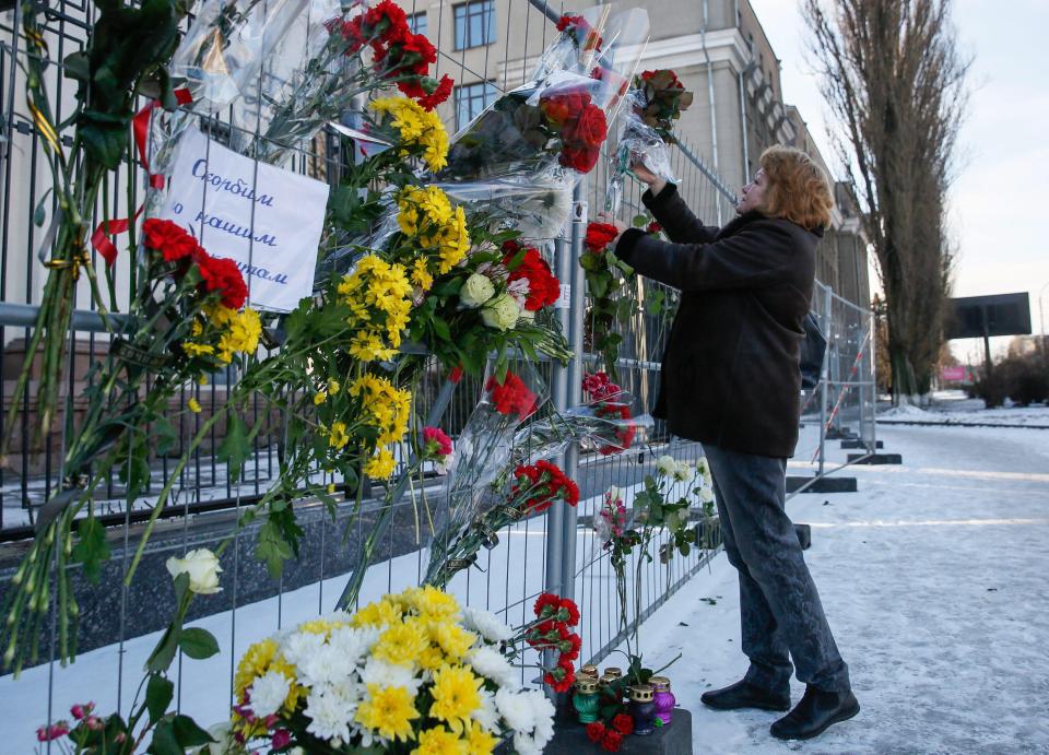  A woman lays flowers to honour the 92 killed in the Christmas Day crash