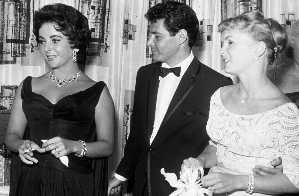  Eddie Fisher stands with arm around wife Debbie Reynolds while looking at Elizabeth Taylor