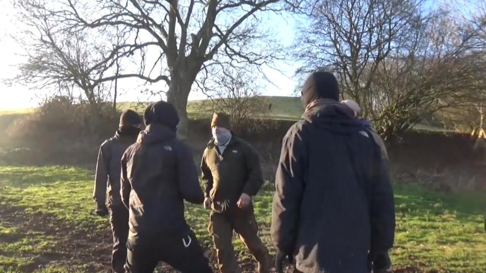  A man with his face covered by a scarf approaches the group of sabs