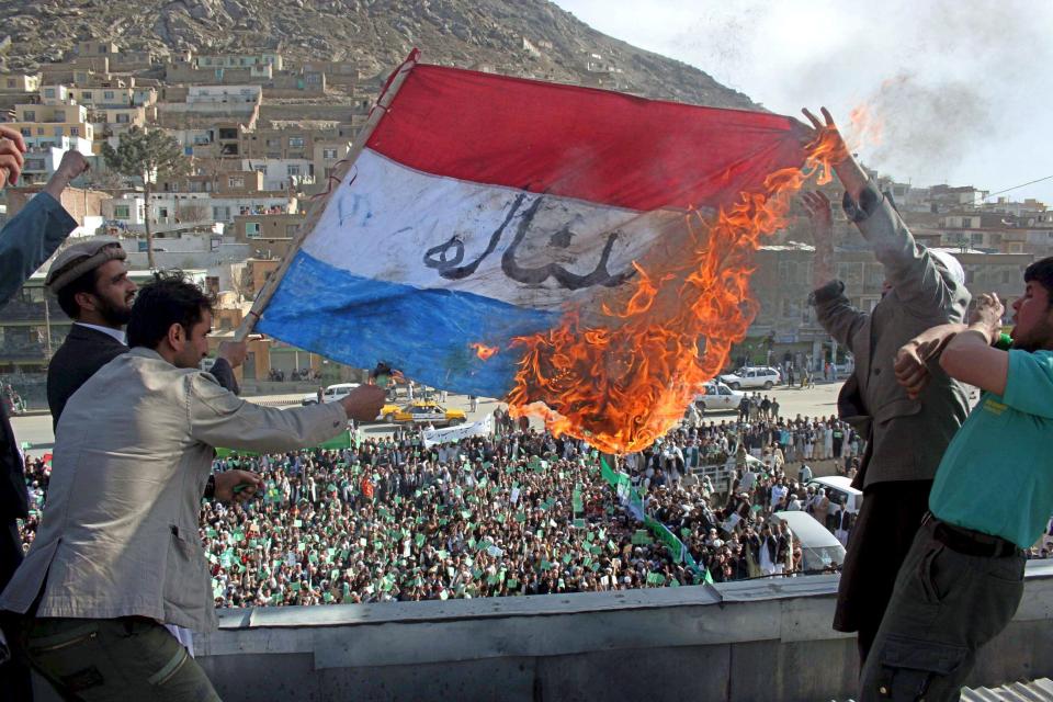  Afghan men burn a Dutch flag during a protest to condemn a controversial film by a Dutch politician Geert Wilders on the Koran