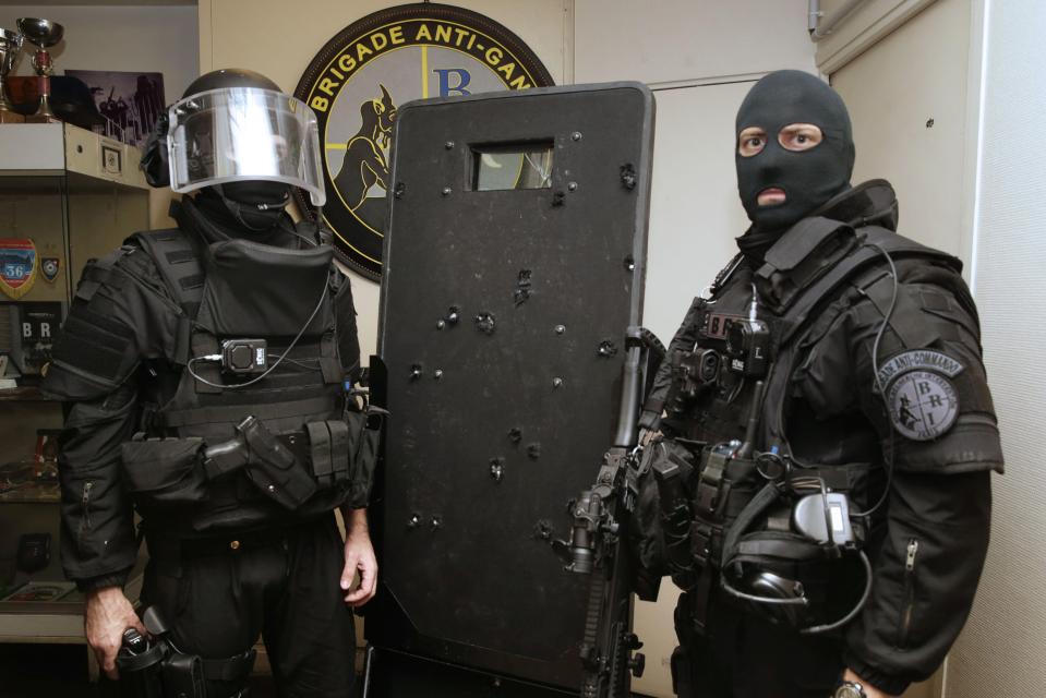  Elite French police commandos pose with a bullet-hole riddled riot shield used during the assault at the Bataclan threatre