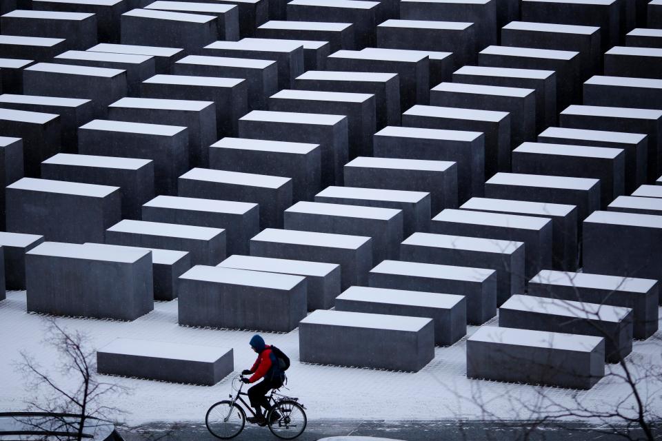  A man on a bike rides past the snow covered Holocaust memorial in Berlin, Germany